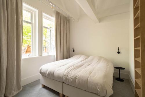 a white bedroom with a bed and a window at Appartement N05 Bakboord & Stuurboord in Oost-Vlieland