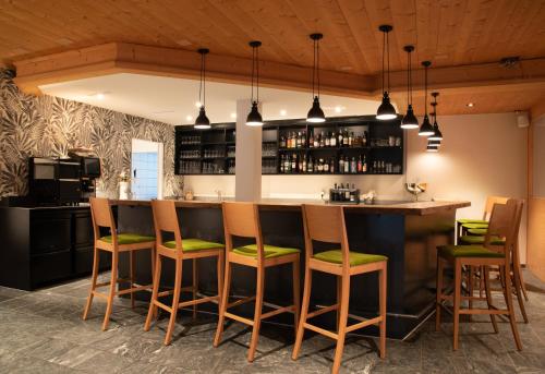 a kitchen with a bar with green cushioned stools at Hotel Alpina in Schiers