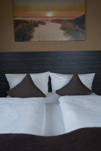 a large white bed with pillows in a bedroom at Hotel Auszeit im Euro Rastpark Guxhagen in Guxhagen