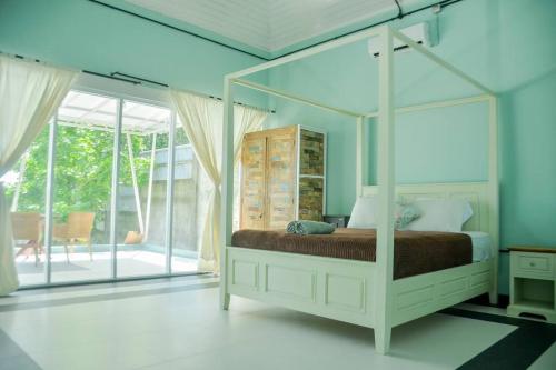 a bedroom with a canopy bed in a room with windows at Hello Belle Villa in Bantul