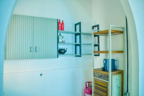 a kitchen with white cabinets and a shelf at Hello Belle Villa in Bantul