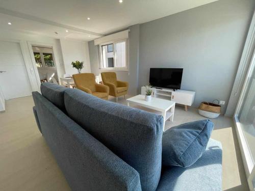 uma sala de estar com um sofá azul e uma televisão em Adosado A 5 hab em Foz