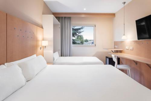 um quarto de hotel com duas camas e uma janela em B&B HOTEL Madrid Arganda em Arganda del Rey