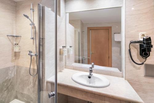 a bathroom with a sink and a shower with a mirror at B&B HOTEL Madrid Arganda in Arganda del Rey