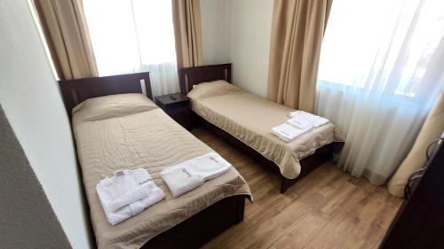 two beds in a hotel room with towels on them at Къща за гости - Вила Сидона in Banya