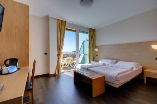 a bedroom with a bed and a desk and a balcony at Hotel Residence Zust in Verbania