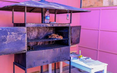 a grill with food cooking on it in a pink wall at Precise Motel in Kampala