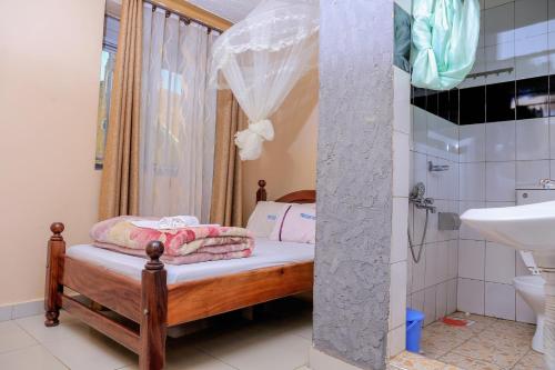 - une petite salle de bains avec un petit lit et un lavabo dans l'établissement Precise Motel, à Kampala