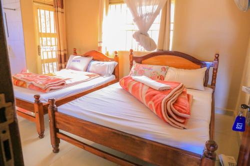 two twin beds sitting in a room with a window at Precise Motel in Kampala