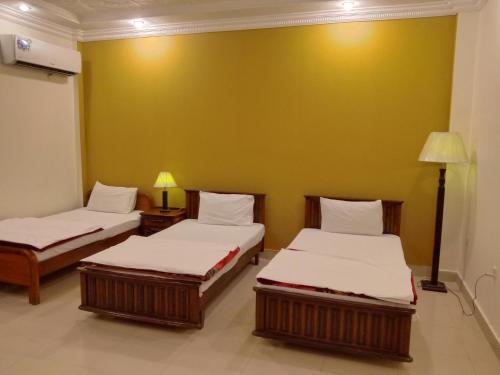 Victoria Guest House في بهاوالبور: سريرين في غرفة بجدار اصفر