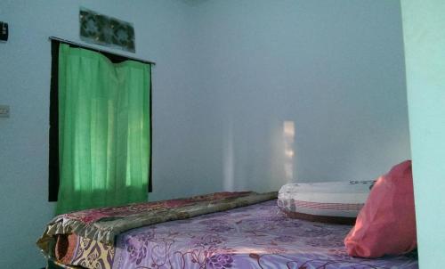 a room with a bed with a green curtain at ADELYA HOMESTAY in Praya