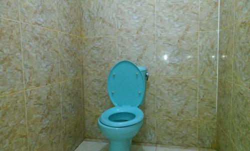 een blauw toilet in een badkamer met een betegelde muur bij ADELYA HOMESTAY in Praya