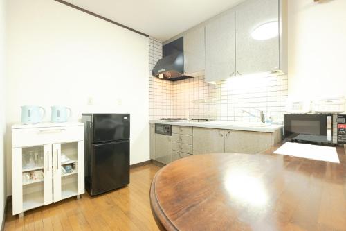 a kitchen with a wooden table and a black refrigerator at STAY IN ASAHIKAWA99 in Asahikawa