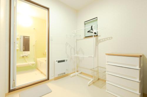 a white bathroom with a shower and a mirror at STAY IN ASAHIKAWA99 in Asahikawa