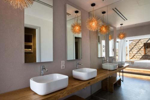 a bathroom with two sinks and two mirrors at Aegean Village Beachfront Resort in Amoopi