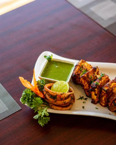 a plate of food with tofu and sauce on a table at Mayur Belgaum Presidency Hotel & Spa in Belgaum