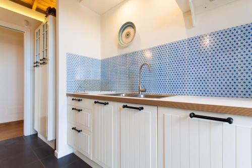 a kitchen with a sink and a blue tiled wall at Villa dell'Ulivo - by DomuSicily in Terrasini