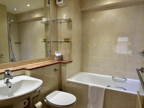 a bathroom with a sink and a toilet and a tub at La Trelade Hotel in St Martin Guernsey