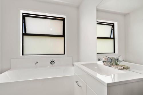 a white bathroom with a sink and two windows at Puna Rise - Taupo Holiday Home in Taupo