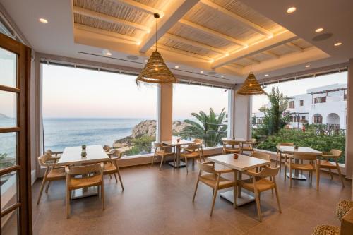 a restaurant with tables and chairs and a view of the ocean at Aegean Village Beachfront Resort in Amoopi
