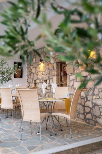 a table and chairs in front of a stone wall at Aegean Village Beachfront Resort in Amoopi