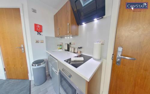 a small kitchen with a sink and a trash can at Victoria House - Deluxe Studios in Coventry City Centre, free parking, by COVSTAYS in Coventry