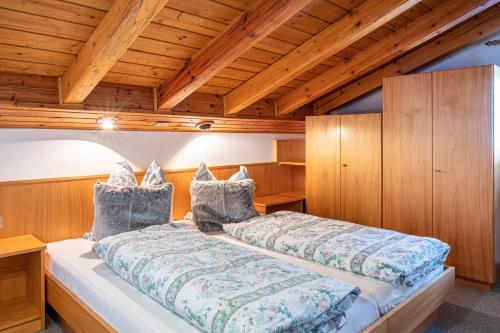 un grande letto in una camera con soffitti in legno di Sirena Carezza Apartment Masarè a Carezza al Lago
