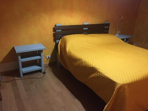 a bed with a yellow comforter and a side table at Affittacamere L’ Agrumeto in Maratea
