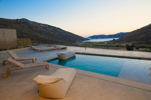 a swimming pool with two lounge chairs at Homa Serifos pool villas in Serifos Chora