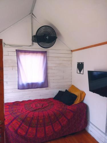 a bedroom with a red bed and a window at Tiny Green House in El Bolsón