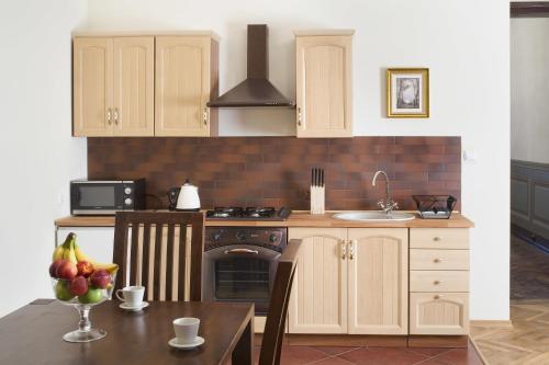 a kitchen with white cabinets and a table and a sink at Apartamenty Gołębia 3 in Krakow