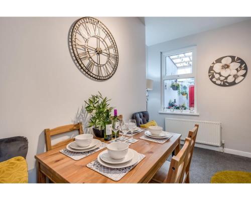 a dining room with a wooden table and a clock on the wall at Central Belfast Apartments Ravenhill in Belfast