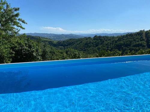 a blue swimming pool with a view of the mountains at IL SEGNAVENTO in Cassinasco