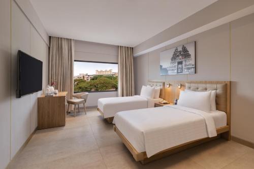 um quarto de hotel com duas camas e uma televisão em Fortune Valley View, Manipal - Member ITC's Hotel Group em Manipala