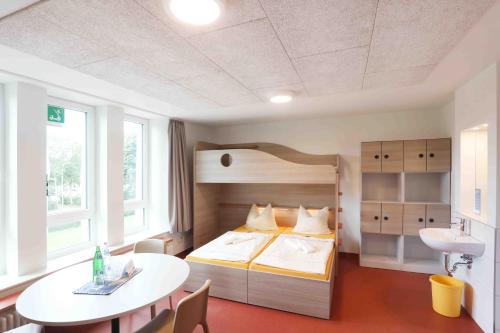 ein Schlafzimmer mit einem Bett und einem Tisch darin in der Unterkunft Jugendherberge Büsum in Büsum