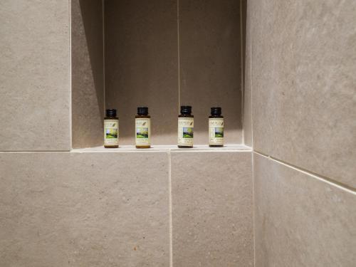 four bottles of essential oils sitting on a shelf in a bathroom at Paradise Resort in Finikounta
