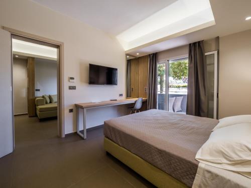 a bedroom with a bed and a desk and a television at Paradise Resort in Finikounta