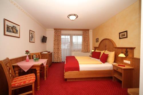 a hotel room with a large bed and a table at Hotel Garni Landhaus Trenkenbach in Schladming