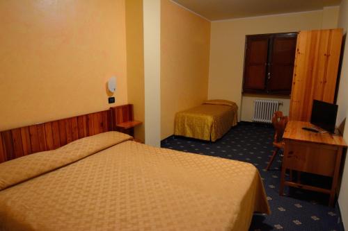 プレトーロにあるGrand Hotel Panoramaのベッド2台とデスクが備わるホテルルームです。