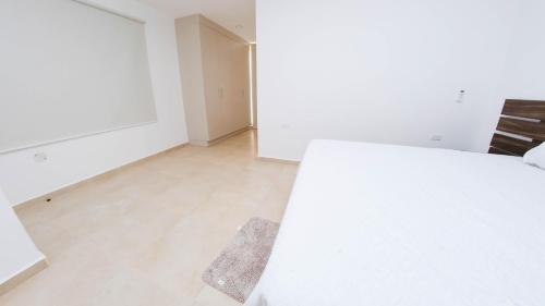 an empty room with a white bed and a wooden floor at Beautiful LOFT in front of Wyndham Hotel in Manta