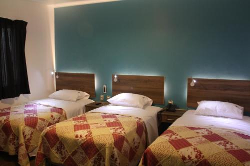 a room with two beds and a blue wall at Hotel Villa Jazmin in Ica