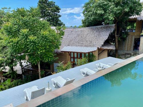 a swimming pool with chairs and a house at Chunut House Resort in Phi Phi Don