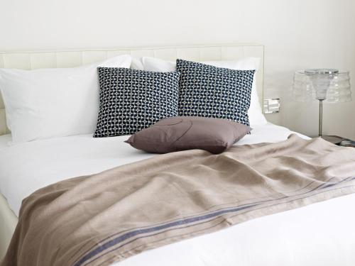 a white bed with pillows and a blanket on it at VISIONAPARTMENTS Berlin - contactless check-in in Berlin