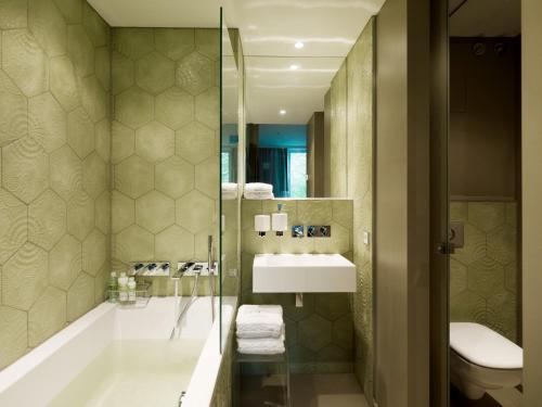 a bathroom with a tub and a sink and a toilet at VISIONAPARTMENTS Berlin - contactless check-in in Berlin