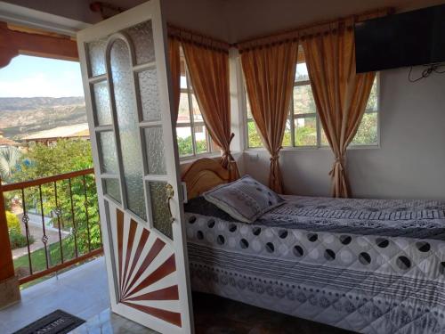een slaapkamer met een bed en een balkon bij Feliz Amanecer in Sáchica