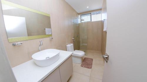 ein Badezimmer mit einem Waschbecken, einem WC und einem Spiegel in der Unterkunft Hermosa Casa en Via Barbasquillo in Manta