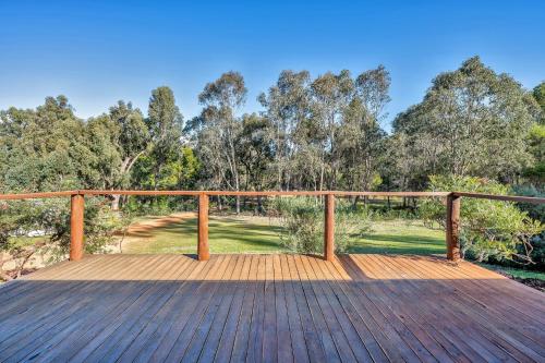 a wooden deck with a fence and trees at Forest Trails House, Dwellingup in Dwellingup