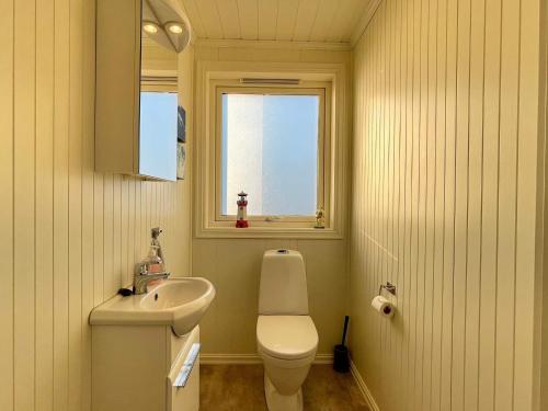 een badkamer met een wastafel, een toilet en een raam bij Holiday home Huglo II in Nordhuglo
