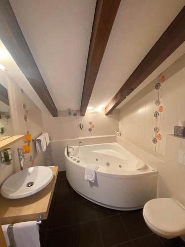 a bathroom with a tub and a sink and a toilet at Hotel Garni Jägerhof in Saas-Fee