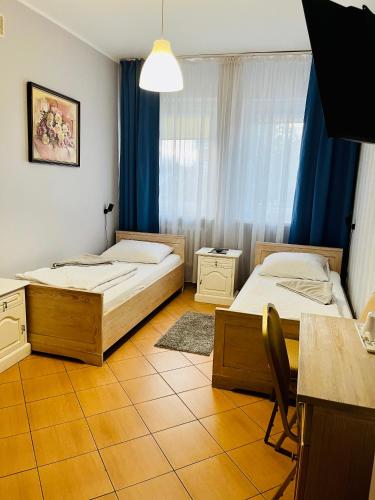 two beds in a room with blue curtains at Hotel Elda in Bydgoszcz